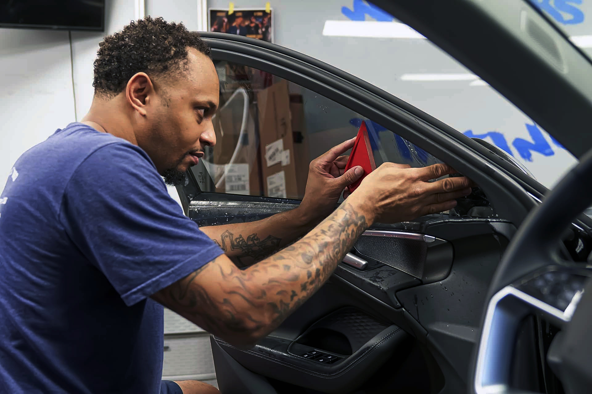 Technician smoothing window tint film along an Audi door window at Warrior's KC