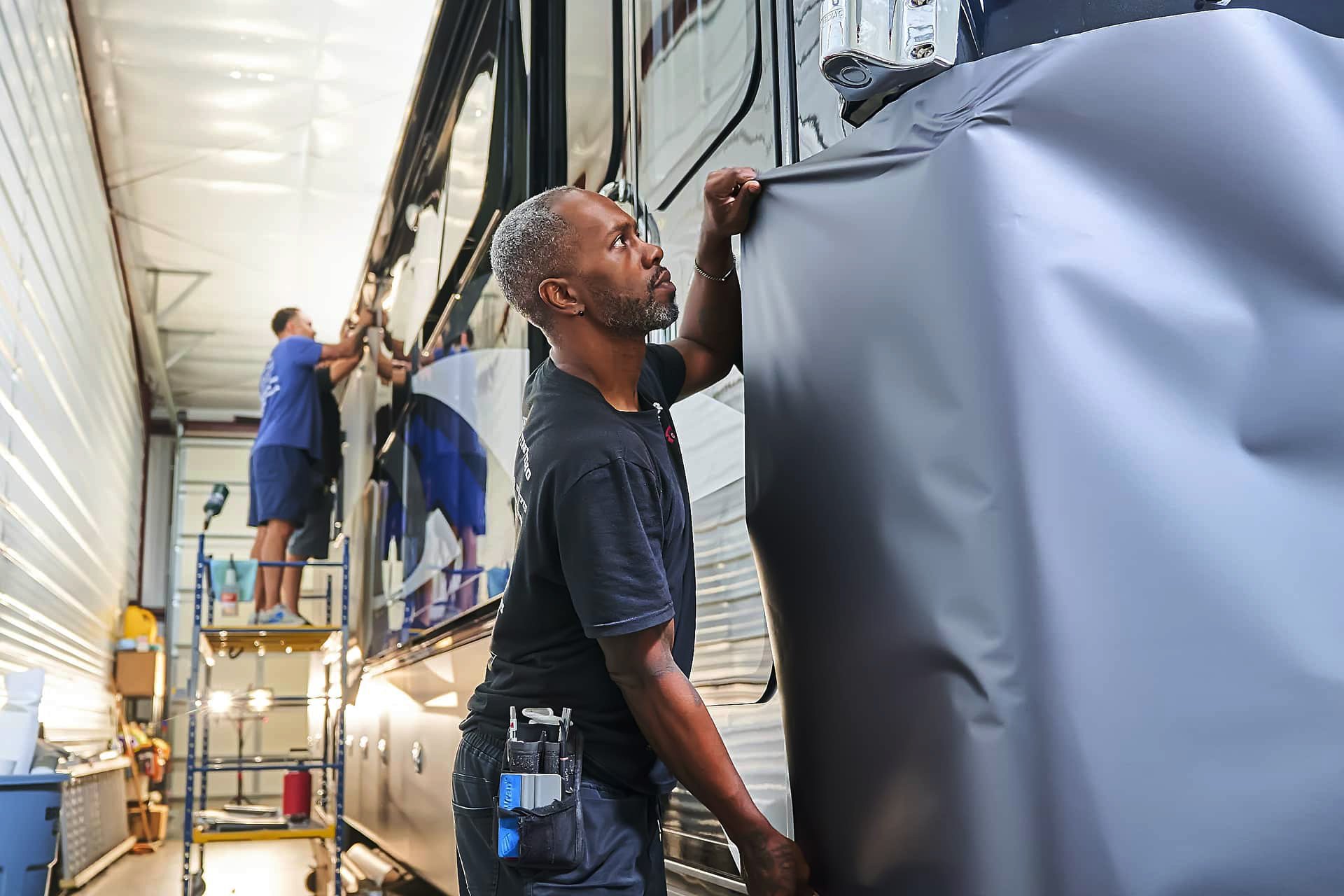Warrior’s KC technician fitting vinyl wrap around a motorcoach