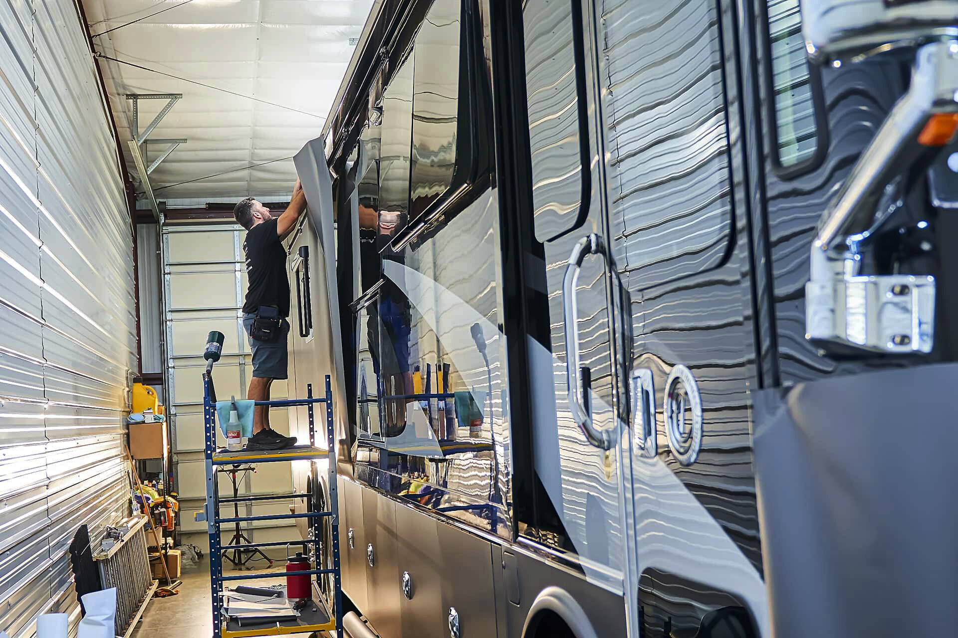 Technician positioning vinyl on the upper side of a Tiffin motorcoach at Warrior's KC (project photo 116)