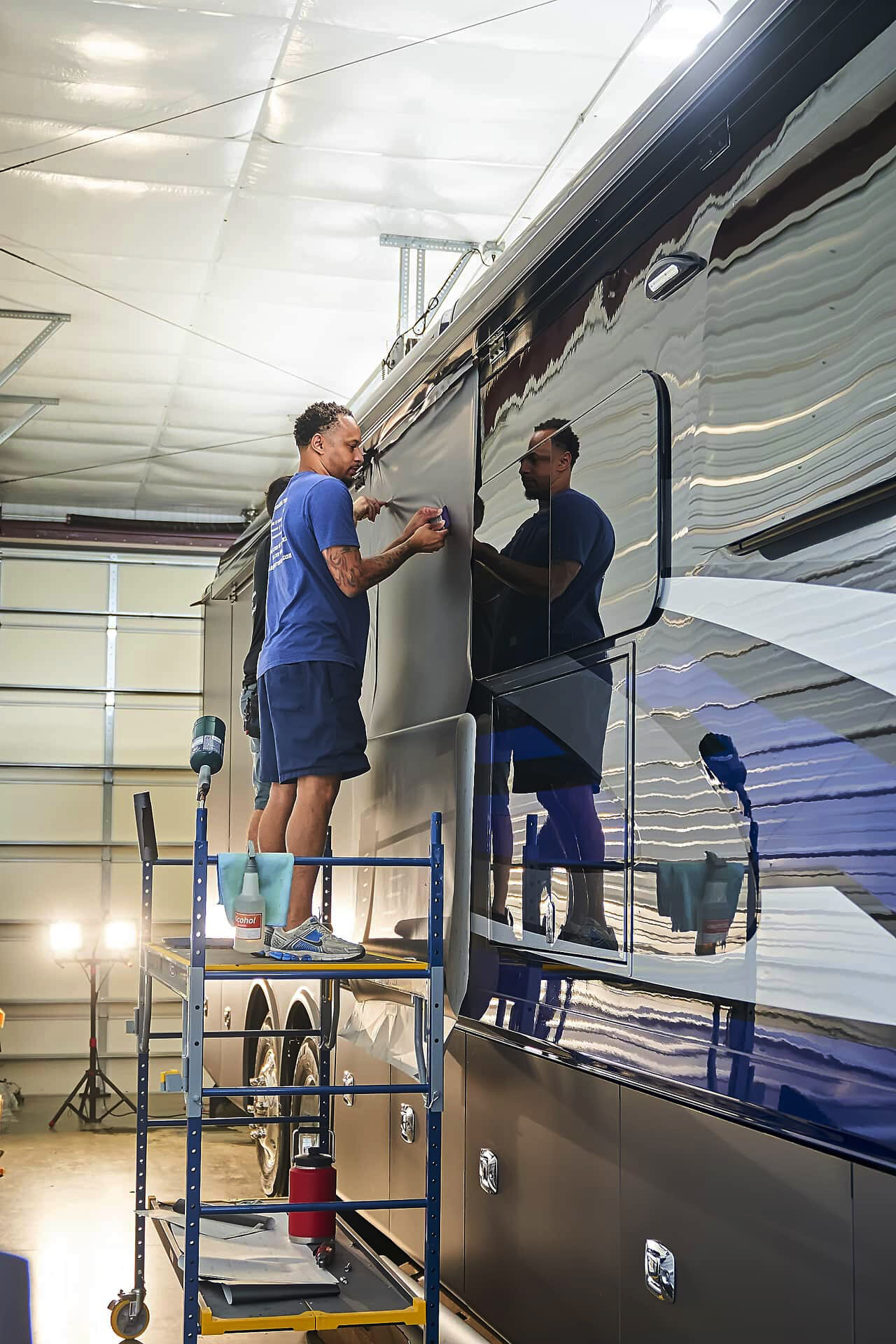 Installer smoothing a vinyl wrap panel along the side of a Tiffin motorcoach (project photo 125)