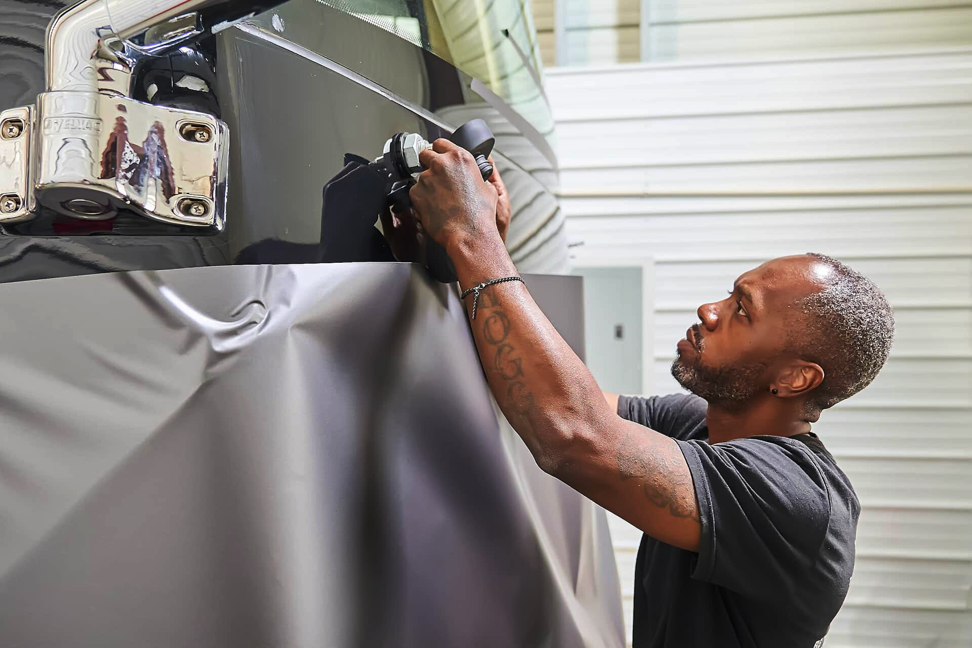 Technician fitting vinyl around front motorcoach hardware (project photo 138)