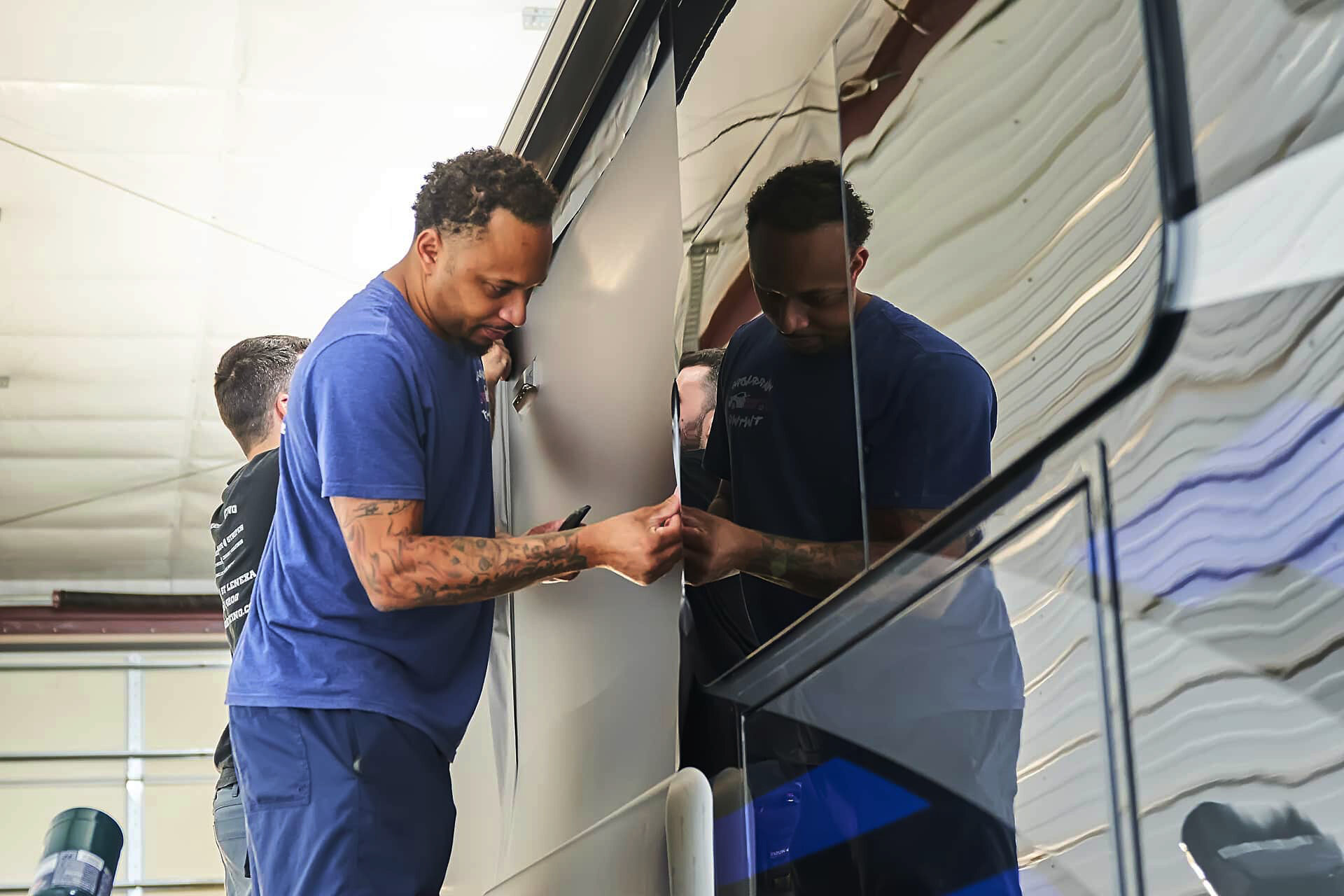 Installer smoothing vinyl beside a motorcoach window (project photo 145)